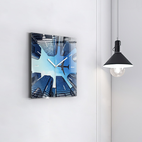Horloge carrée en verre Avion au-dessus des bâtiments